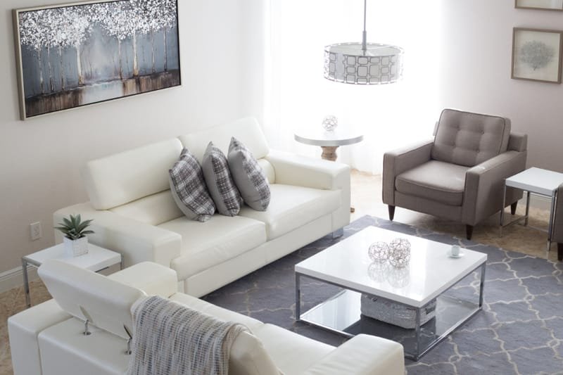 A bright, modern living room with a white sofa and large windows